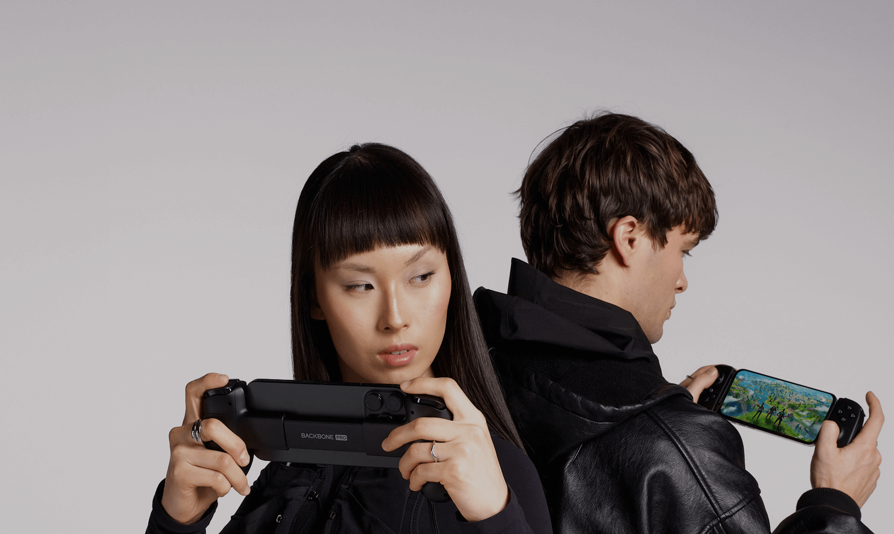 Two people playing video games with controllers on a plain background